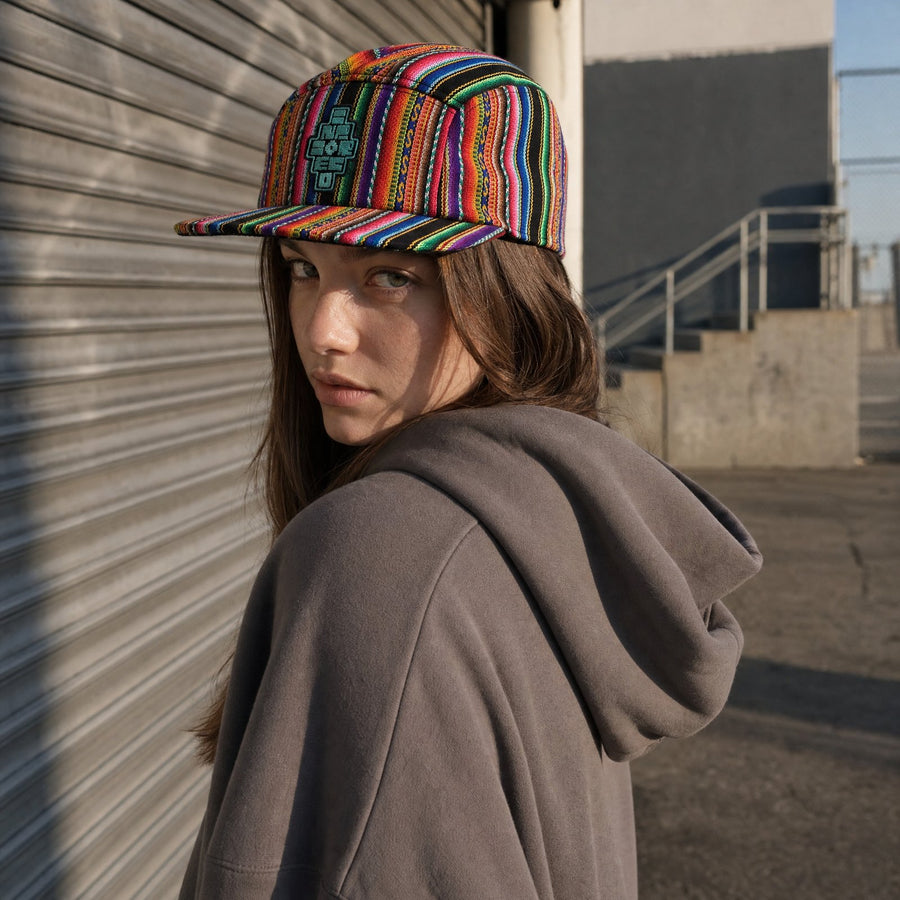 A woman wearing the handwoven Andean camp cap beside a steel shutter